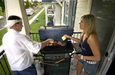 
At the Adirondack Village apartments on the South Hill, Bryce Ells and Crystal Acker help barbeque hamburgers on the balcony of a friend's apartment.
 (Colin Mulvany / The Spokesman-Review)