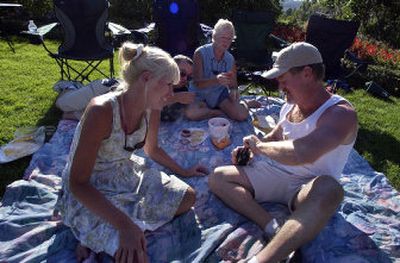 
From left, Cheryl Culbertson, Mark Morrissey and Cheri Morrissey wait as Stephen Davis opens a bottle of wine during a concert at Arbor Crest last year. The summer concert series at the Spokane Valley winery starts Sunday.
 (File/ / The Spokesman-Review)