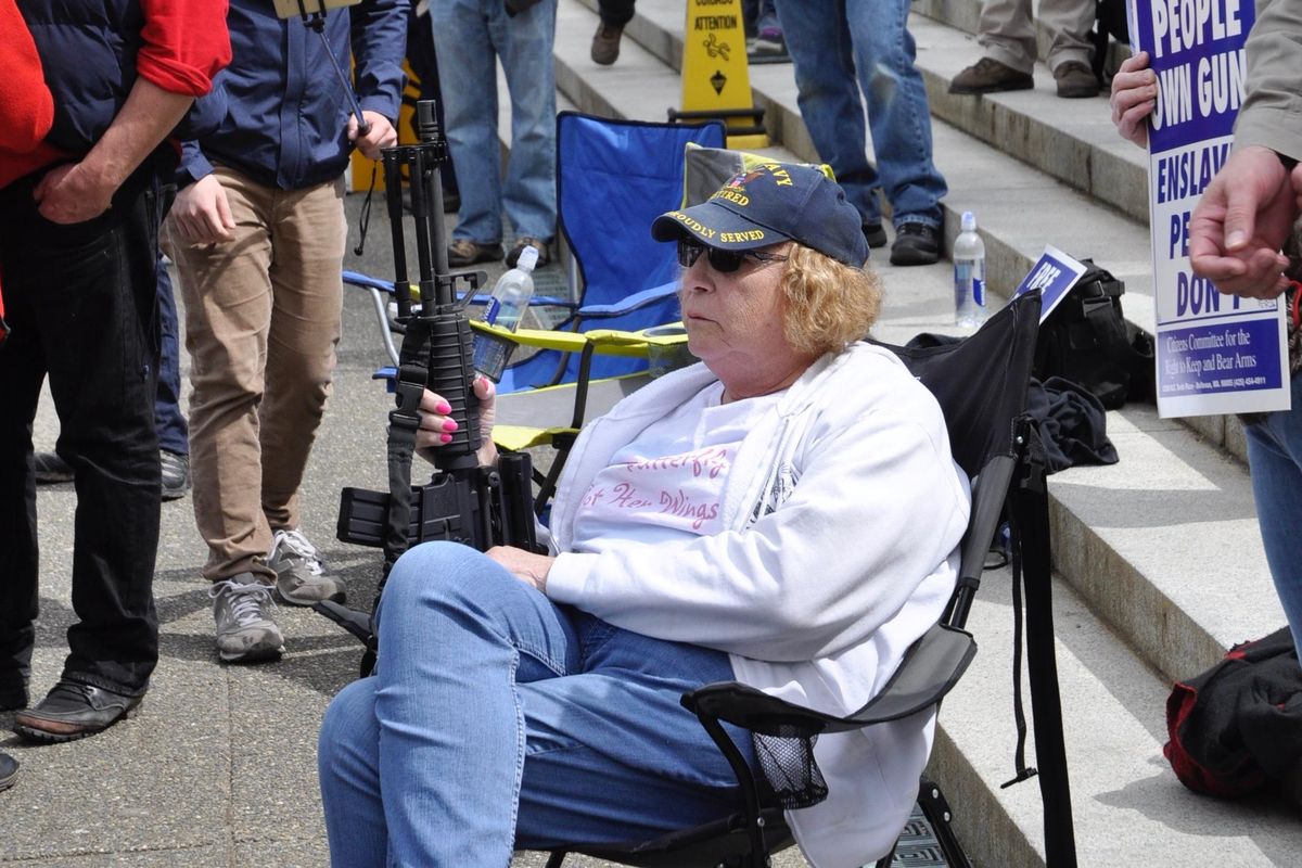 OLYMPIA – With her AR-15 and a camp chair, Christine Bilyeu listens to speakers at the gun rights rally at the Capitol. (Jim Camden / The Spokesman-Review)