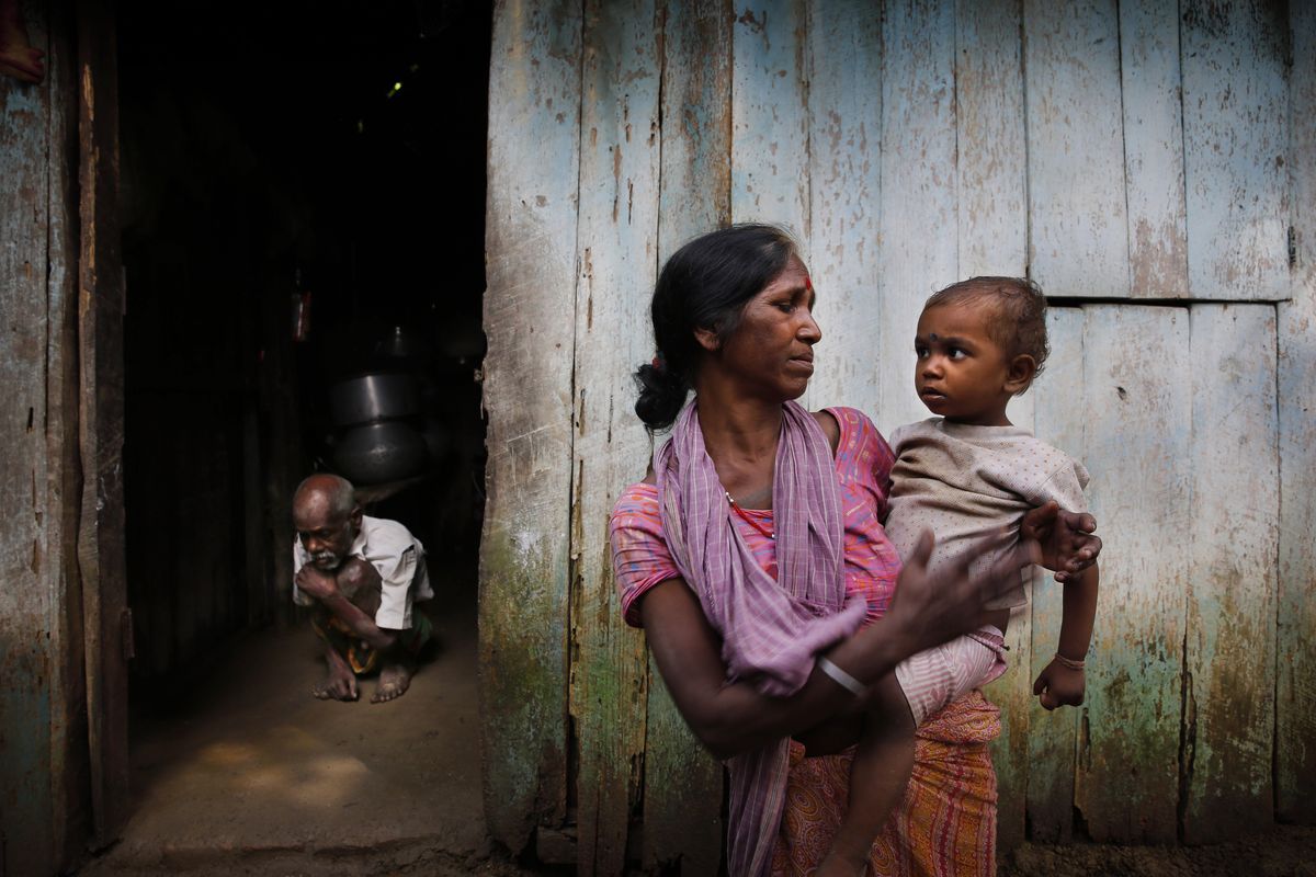 Tea worker Chitramani Mahali holds her son as her ailing father-in-law tries to come out from the house in Bundapani, 75 miles from Siliguri in the Indian northeastern estate of West Bengal, on Aug. 25. When the Bundapani tea estate closed last year, death arrived soon after. Seven workers died in the two months it took the government to become aware of the crisis, and the toll has continued to climb since. (Associated Press)