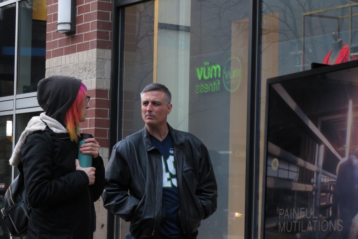 Activist Arica O’Dell speaks with passerby Larry Caber near River Park Square on Jan. 25 as protesters hold TVs showing footage from inside slaughterhouses. (Jonathan Glover / The Spokesman-Review)