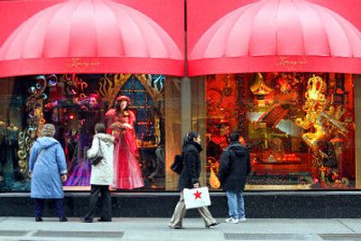 
Pedestrians look at the Bloomingdale's Christmas windows as another, center, with a Macy's shopping bag walks by, on Monday in New York. The nation's retailers had a modest start to the holiday shopping season.  
 (Associated Press / The Spokesman-Review)
