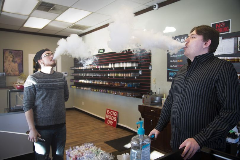 Gabriel Feller, left, and Luke Patterson release clouds of vapor at Smokin’ Legal Vaperz vaping shop on Dec. 16, 2015. The two are salespeople at the shop, which sells vaping devices and juices that are inhaled using the battery-powered devices, sometimes called e-cigs. (Jesse Tinsley / The Spokesman-Review)