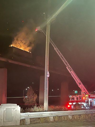 A photo provided by the Spokane Fire Department shows firefighters extinguishing a blaze inside a train car on top of a bridge near Browne’s Addition on Thursday evening.  (Courtesy Spokane Fire Department)