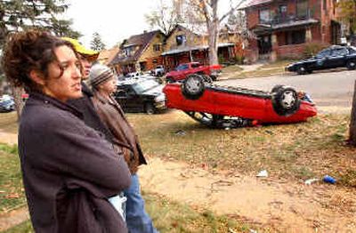 
University of Colorado sophomore Annika Salinas, left, looks over her overturned car Sunday morning in Boulder, Colo. 
 (Associated Press / The Spokesman-Review)