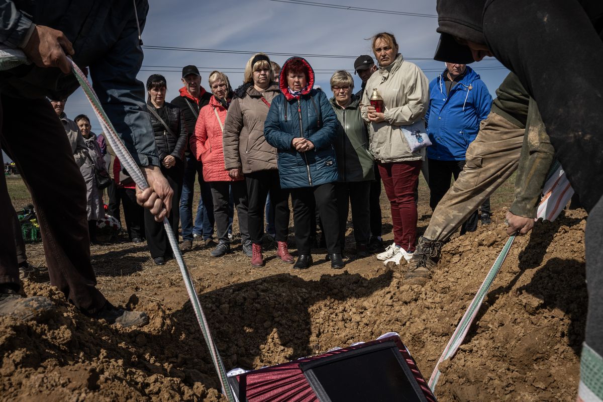 Friends and family members watch as a coffin containing the body of Volodymyr Butenko, who died from a missile strike in Sumy, is lowered into the ground Thursday, in Sumy, Ukraine. MUST CREDIT: Ed Ram/For The Washington Post  (Ed Ram/For The Washington Post)