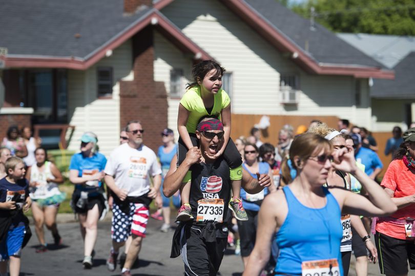 Sylvan Tessitore holds on for dear life to her father Antonio as he runs toward the finish line with her on his back during Bloomsday 2016 on Sunday, May 1, 2016, in Spokane, Wash. (Tyler Tjomsland / The Spokesman-Review)