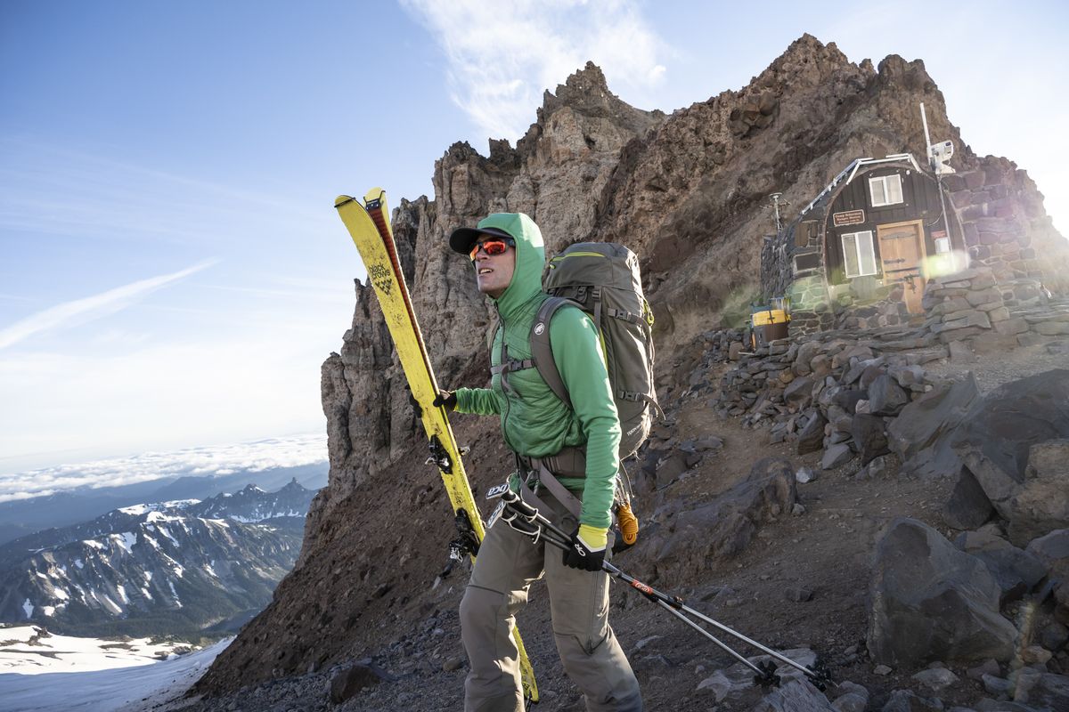 Trevor Kostanich carries his skis across the rocky ridge in front of Camp Schurman below the prominent rocks of Steamboat Prow. This point was reached at approximately 6 a.m. on day one, five hours after leaving the Glacier Basin trailhead near the White River campground. Camp Schurman is located at 9,400 feet on the northeast side of Mount Rainier, and serves as the jumping off point for the Emmons/Winthrop climbing route.  (Scott Rinckenberger)