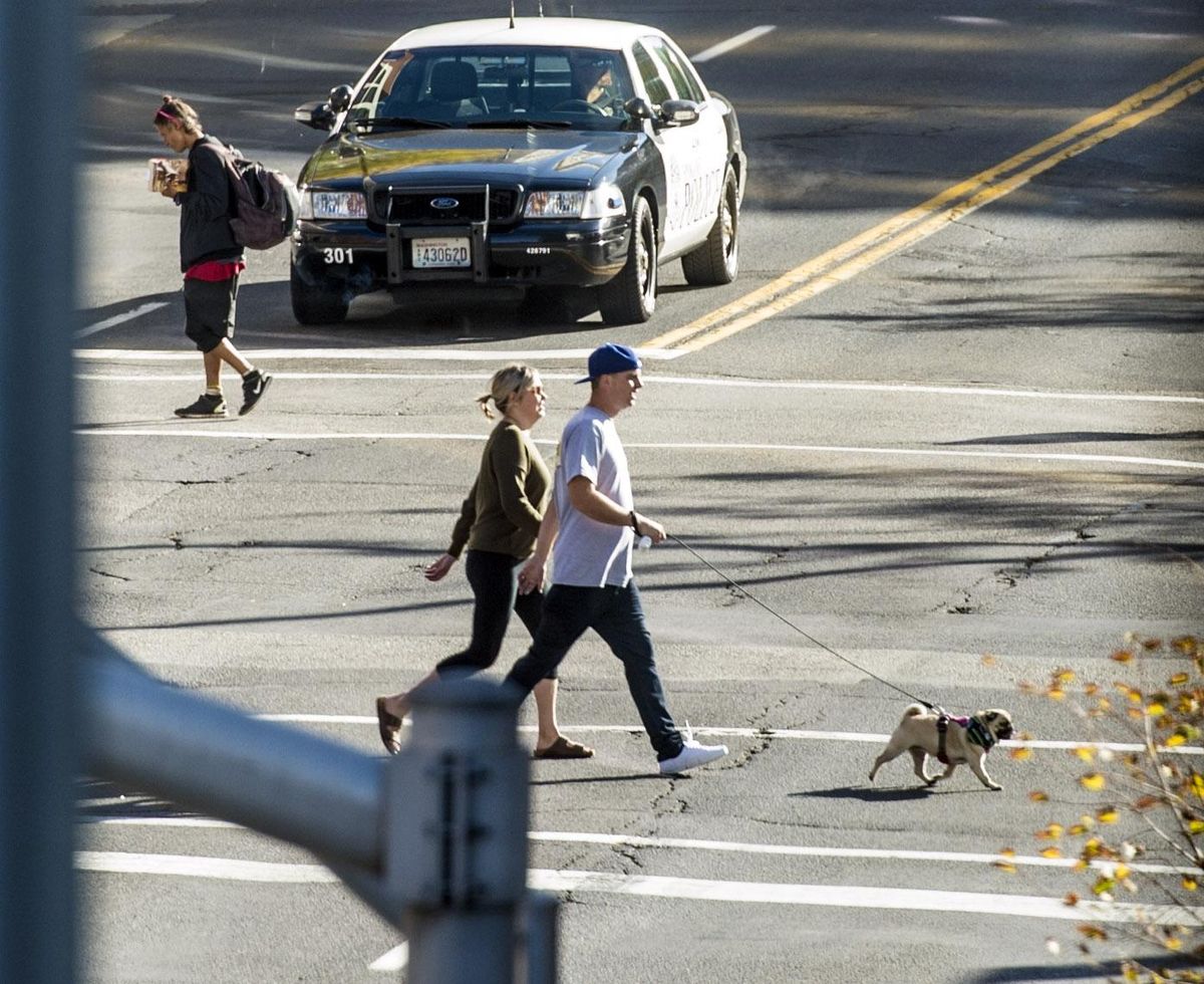 Pedestrians cross Riverside Avenue at Howard Street on Sunday, Oct. 1, 2017, in front of a police car in downtown Spokane. (Dan Pelle / The Spokesman-Review)