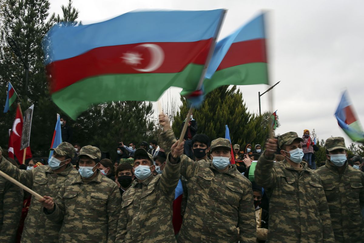 Azerbaijani soldiers wave national flags as they celebrate the transfer of the Lachin region to Azerbaijan