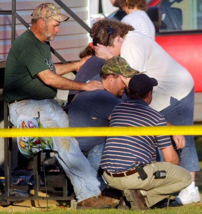Family members of victims of a shooting rampage comfort each other  in Samson, Ala., on Tuesday.  A coroner says the  suspect burned down his mother’s house where officials found her body.  (Associated Press / The Spokesman-Review)
