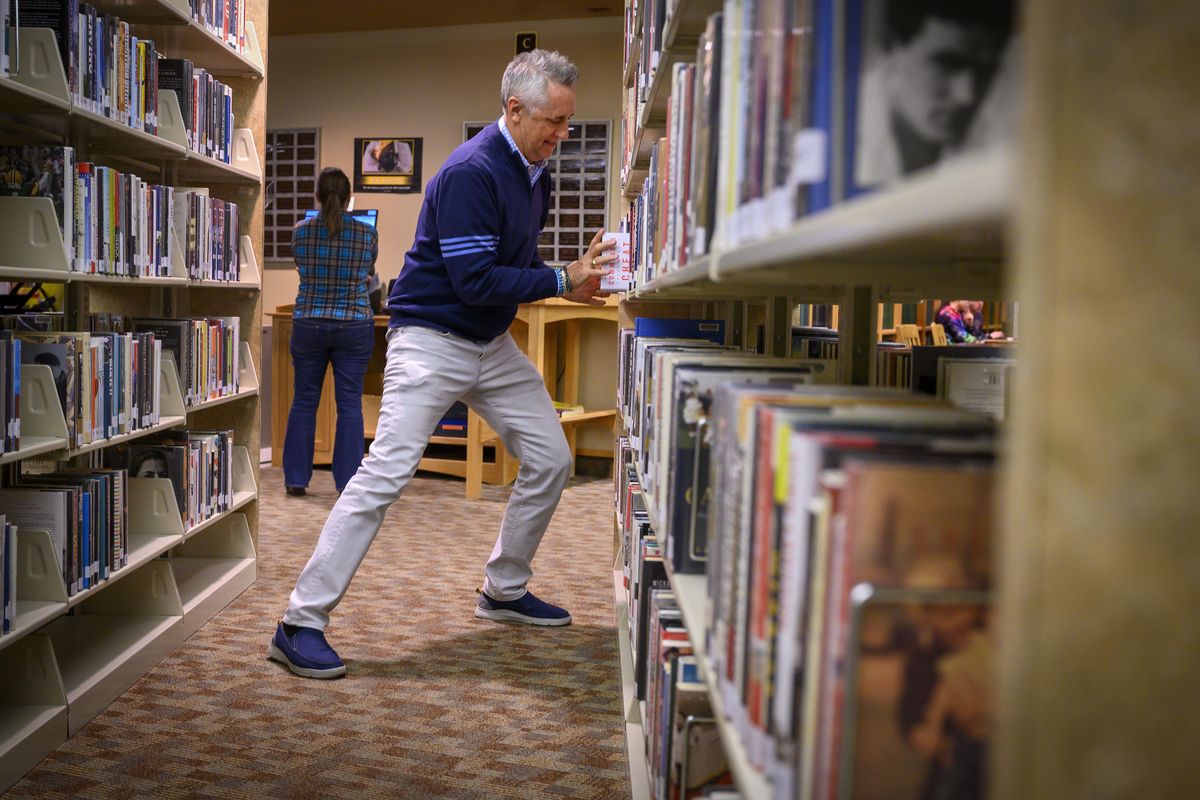 Screenwriter and author Rick Reilly, who gained fame as a Sports Illustrated columnist, hides 10 copies of his book “Commander in Cheat: How Golf Explains Trump” around Coeur d’Alene Public Library on Thursday  in Coeur d’Alene. (Colin Mulvany / The Spokesman-Review)