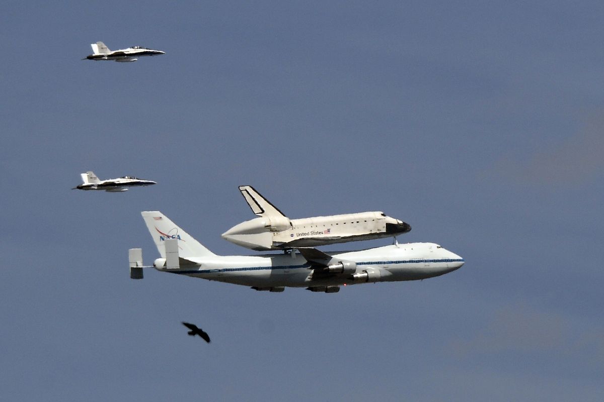 The Space Shuttle Endeavour atop a modified 747 flies followed by two chase planes and a bird as near Dodger Stadium, Friday, Sept. 21, 2012, in Los Angeles, on a sightseeing tour of California, the last aerial hurrah before retiring to a Los Angeles museum. (Mark Terrill / Associated Press)