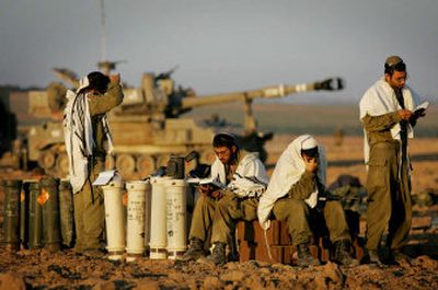 
Israeli artillery gunners pray as they sit on shells next to an armored vehicle near Kibbutz Nahal Oz, just outside the northern Gaza Strip, on Sunday. 
 (Associated Press / The Spokesman-Review)