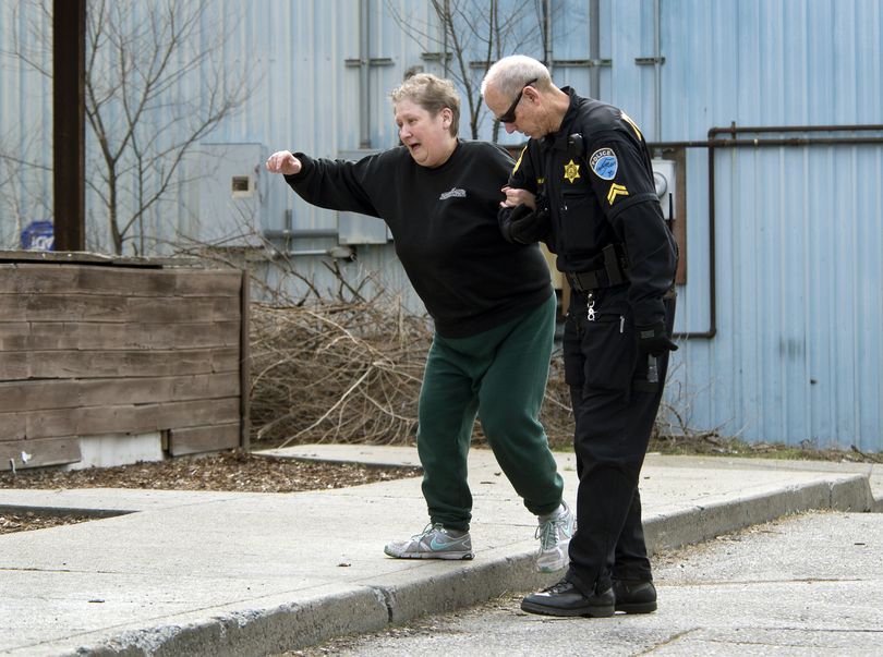 Spokane Valley Police Cpl. Jim Wakefield assists the manager of Poppy’s Tavern up onto a sidewalk after she had her hands bound with zip ties and was robbed Wednesday morning by an armed gunman. She freed herself from the ties after about 10 minutes. (Dan Pelle)