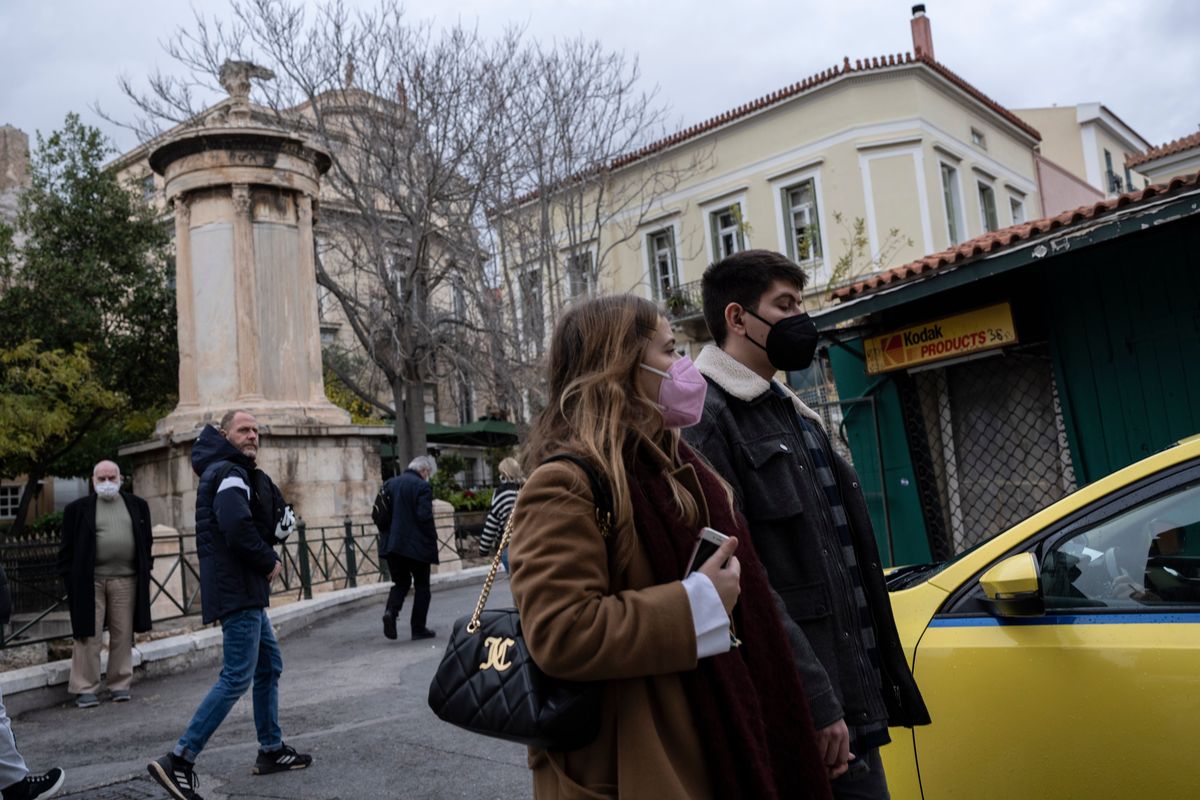 People wearing protective face masks walk in Plaka, district of Athens, on Tuesday, Dec 28, 2021. Greek authorities are blaming the rapid spread of the omicron variant for a record level of infections and have announced new restrictions that will take effect early on the new year.  (Petros Giannakouris)
