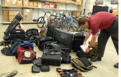 
Bill McLeod of the Coeur d'Alene Police Department places a digital projector among the laptops, televisions and other recovered items at  the evidence room Thursday. 
 (Jesse Tinsley / The Spokesman-Review)