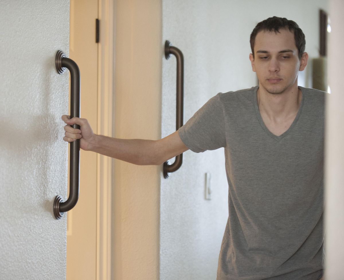Peter De Mint, one of three Yorba Linda, Calif., brothers who suffer from ataxia, uses hand bars to navigate a hallway on September 6, 2016. Ataxia is a rare neurological disorder that affects movement and reaction time. (SAM GANGWER / TNS)