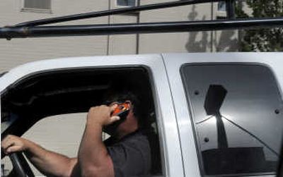 
A motorist talks on his cell phone while waiting in a traffic backup at the corner of Lincoln and  First Avenue in Spokane on June 20. 
 (Dan Pelle / The Spokesman-Review)