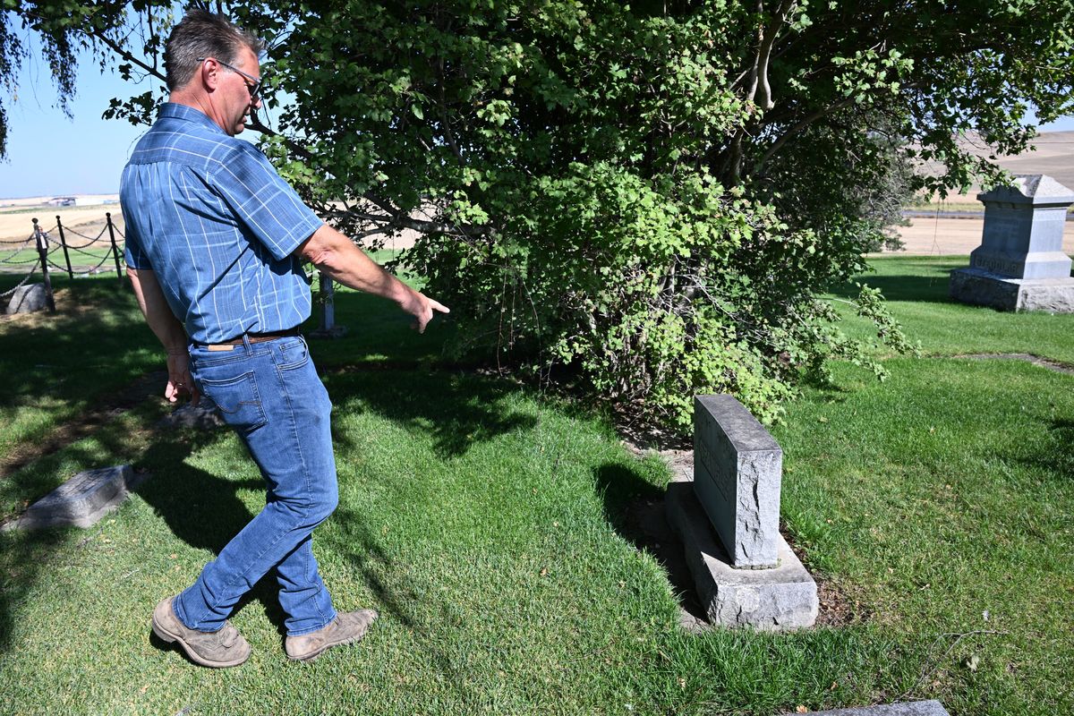 Robert Sievers, a farmer and the secretary for the Spangle Cemetery District, points to a historic headstone Friday with the name Spangle on it, likely the family for whom the town is named. The Spangle Cemetery District is seeking a levy in the November election to cover costs to maintain the cemetery.  (Jesse Tinsley/THE SPOKESMAN-REVIEW)