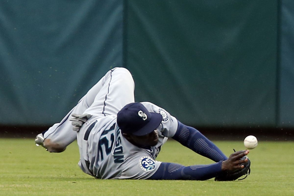 Mariners left fielder Trayvon Robinson fails to corral a ball hit by Rangers’ Michael Young in the seventh inning. (Associated Press)