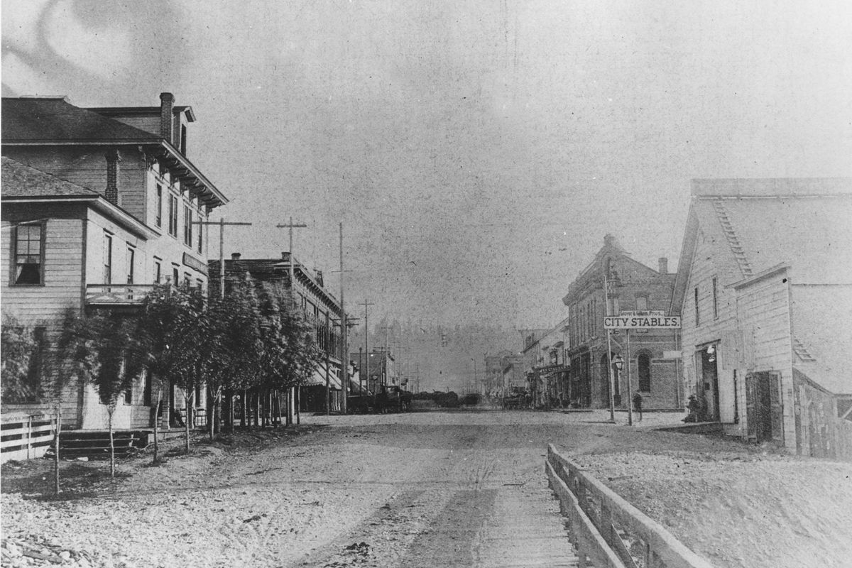 Mid-1880s: This view of Howard Street looks south from the south edge of the river. The Howard Street Bridge, the first bridge in Spokane, is in the foreground. The intersecting street is Trent, now Spokane Falls Boulevard. The building to the left is the California House hotel, and on the right is the Glover Stables.