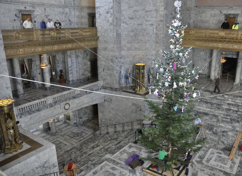 OLYMPIA -- State workers hoist the Holiday Kids Tree into its stand in the Capitol Rotunda by pulling on ropes from the Third Floor Balconies. The 34-foot noble fir was donated by Winkleworld Tree Farm in Olympia and the donated cash and toys are handled by the Association of Washington Business (Jim Camden)