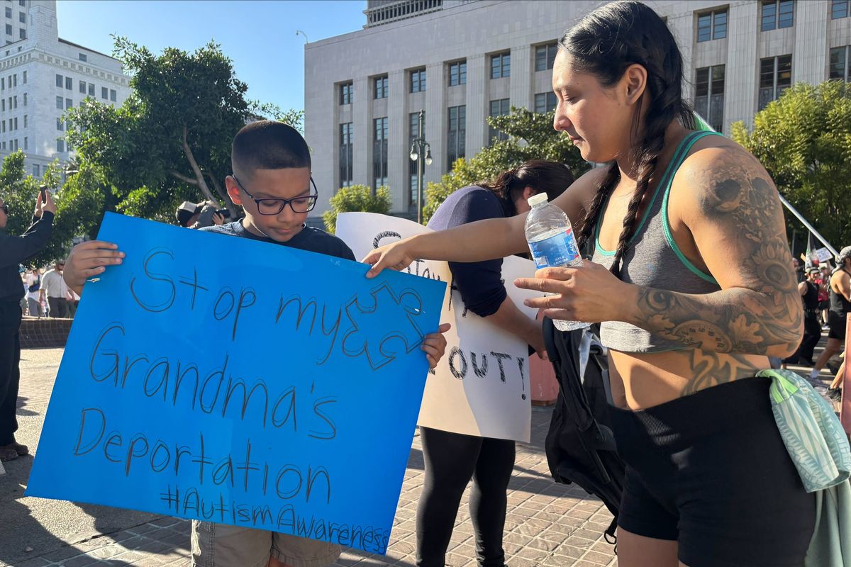 Cristal Lopez and her son hold a sign calling attention to their relative facing deportation, according to Lopez. They were among the hundreds of people marching on Friday in Los Angeles as part of a wider protest over U.S. Immigration and Customs Enforcement.   (USA Today)