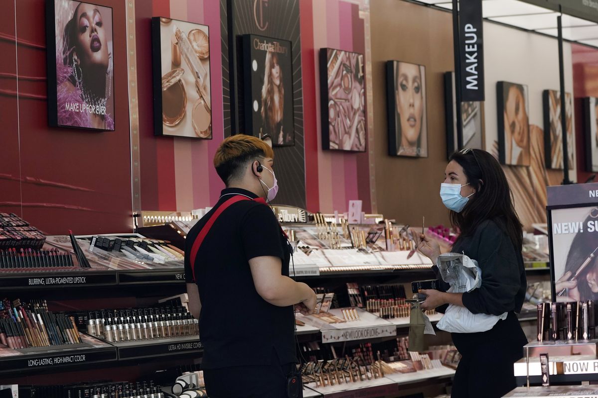 A worker, at left, tends to a customer at a Los Angeles cosmetics shop on Thursday, May 20, 2021.  (Associated Press)