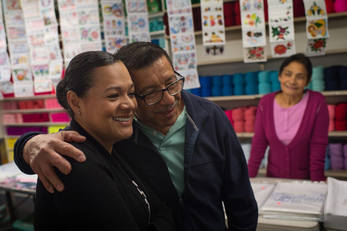 Gloria Ochoa-Bruck is embraced by her father, Simon Ochoa, 66, as they stand in the store he started with his wife, Anita, 60, at right,  Monday in Pasco. (Tyler Tjomsland / The Spokesman-Review)