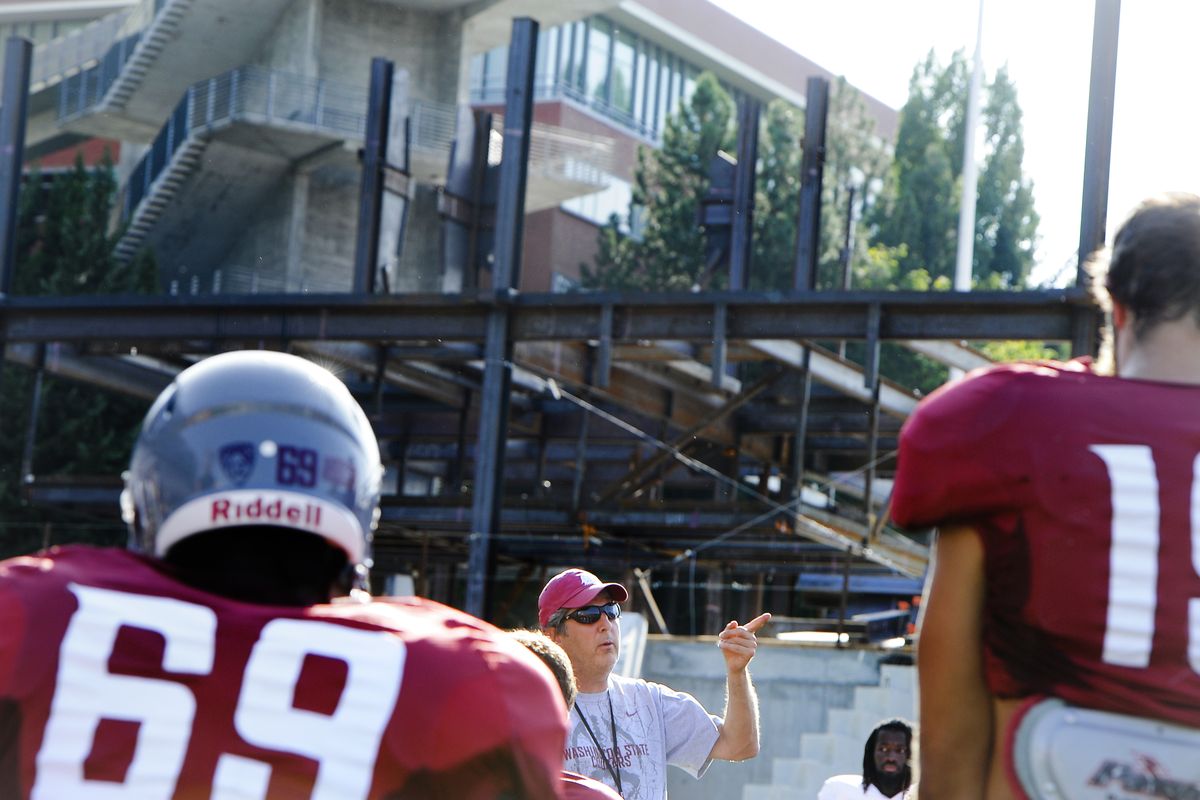 Washington State Cougars head coach Mike Leach builds his football team amidst the construction workers who are also building a football program. (Tyler Tjomsland)