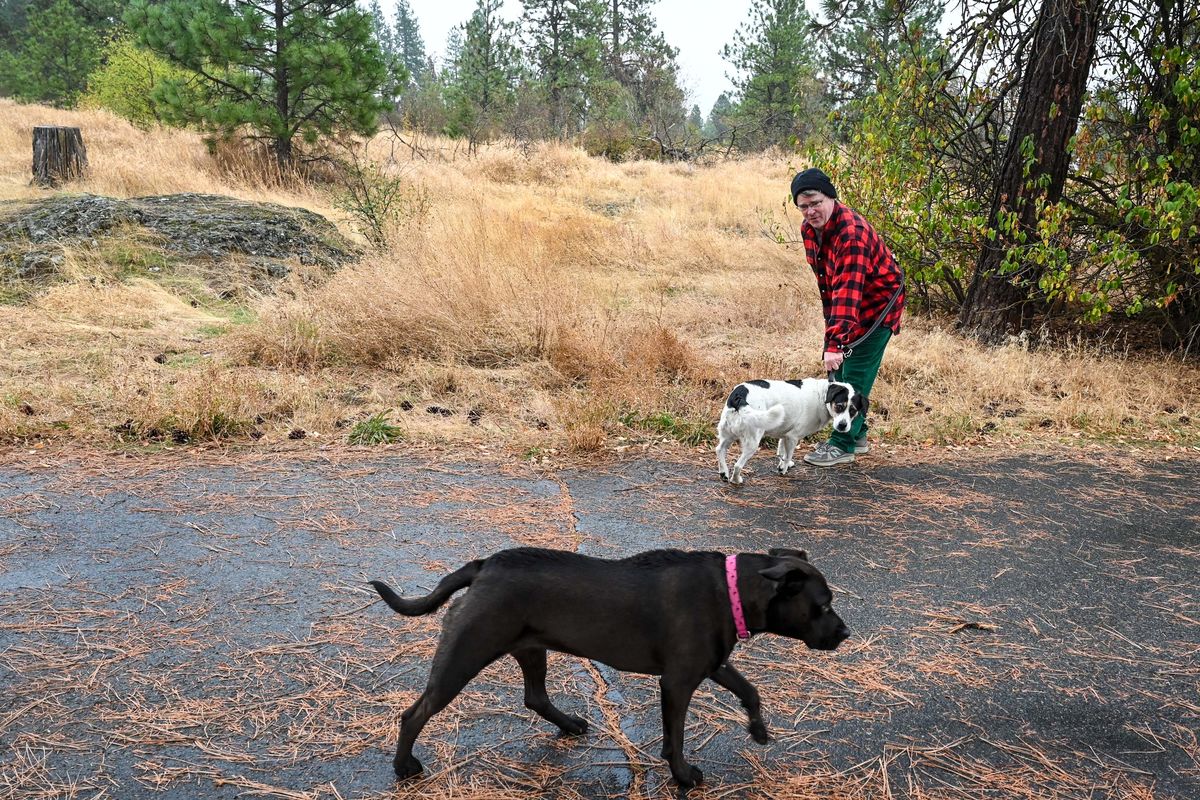 John Spencer has a hold of his dog, Mochie, as another dog passes during a walk in upper Lincoln Park in Spokane in this October 2021 photo. Once a proposed location for a potential dog park, it was later abandoned in favor of another proposal along Upriver Drive that was discussed Thursday.  (Dan Pelle/THESPOKESMAN-REVIEW)