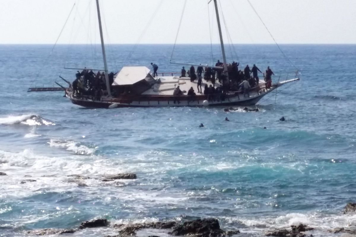 Migrants swim to reach the shore as others remain on a listing vessel that sank later Monday off the coast of Greece. Greek authorities said at least three people on the boat died, including a child. (Associated Press)