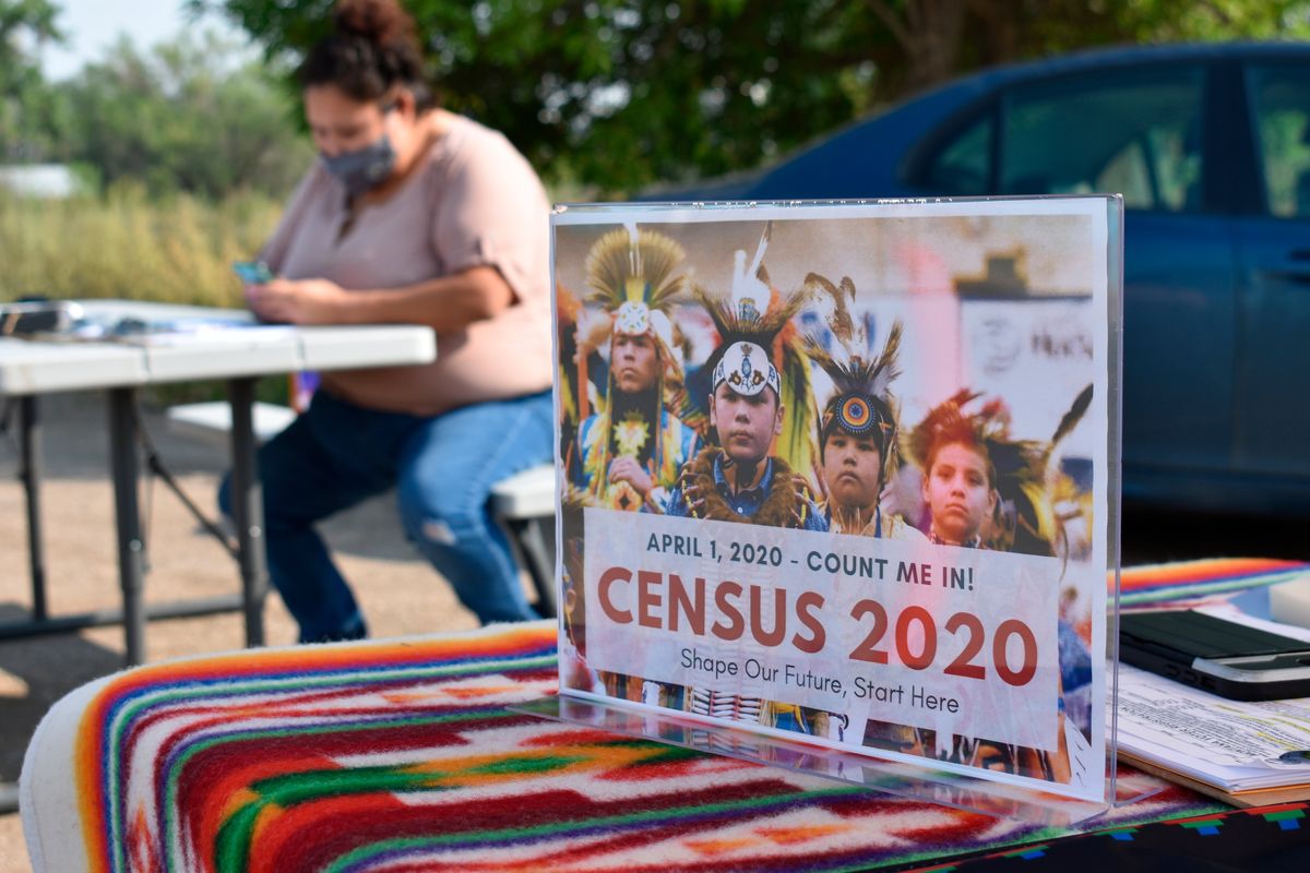 A sign promoting Native American participation in the U.S. census is displayed as Selena Rides Horse enters information into her phone on behalf of a member of the Crow Indian Tribe on Aug. 26, 2020, in Lodge Grass, Mont.  (Matthew Brown)