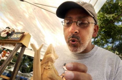 
Wood carver Dave Francis of Castlegar, B.C., cleans his latest Santa carving at his booth at Coeur d'Alene's downtown Street Fair.  
 (Jesse Tinsley / The Spokesman-Review)