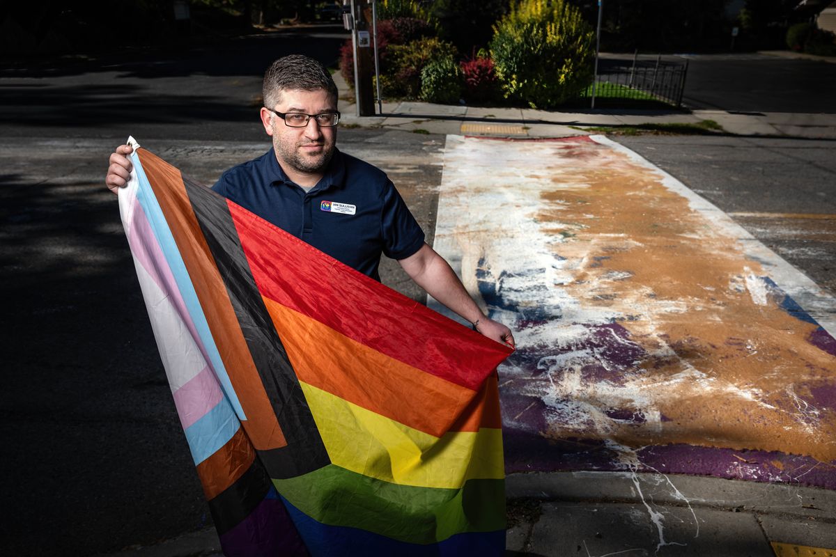 “It’s not going to silence us,” said Odyssey Youth Movement Executive Director Ian Sullivan, who is shown holding an LGBTQ+ flag at the vandalized Pride crosswalk Friday at 12th Avenue and Perry Street.  (COLIN MULVANY/THE SPOKESMAN-REVIEW)