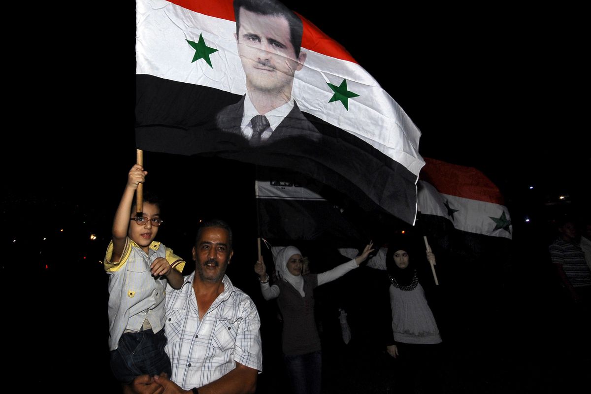 Syrians carry national flags depicting President Bashar Assad, after Assad’s interview on state-run TV, in Omawiyeen Square, Damascus, Syria, on Sunday. (Associated Press)