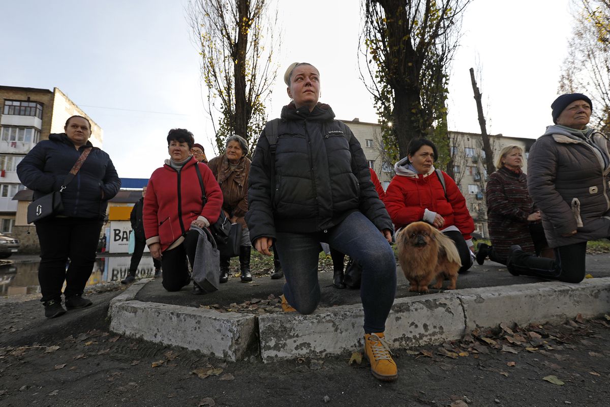 Residents of Borodyanka, Ukraine, kneel as the procession for fallen soldier Oleksii Kozlenko, 32, passes on Nov. 9, 2022.    (Carolyn Cole/Los Angeles Times/TNS)