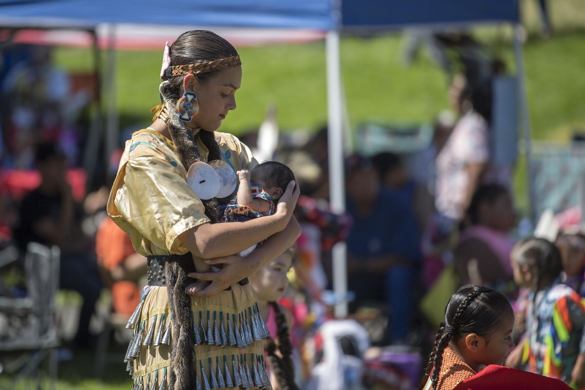 Mailani Carita carries her one-month-old sister in the dance arena of the Gathering At The Falls Powwow Saturday, Aug. 26, 2017, in Riverfront Park in Spokane. (Jesse Tinsley / The Spokesman-Review)