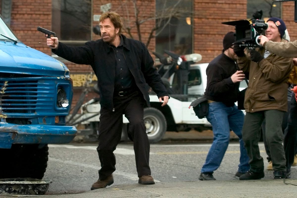 At the intersection of Broadway Avenue and Lincoln Street, actor Chuck Norris takes a shot at the bad guys on Dec. 10, 2004, during filming of the North by Northwest movie production of “The Cutter.”  (COLIN MULVANY/The Spokesman-Review)