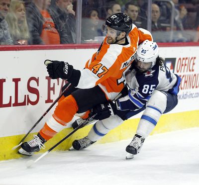 Philadelphia Flyers' Andrew MacDonald, left, and Winnipeg Jets' Mathieu Perrault vie for the puck during Saturday’s game. (Tom Mihalek / Associated Press)