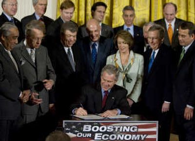 President Bush, surrounded by Congress and Cabinet members, signs the Economic Stimulus Act of 2008 on Wednesday in the East Room of the White House. In the front row, from left, are Rep. Charles Rangel, D-N.Y.; Senate Majority Leader Harry Reid, of Nevada; House Minority Whip Roy Blunt, of Missouri; Treasury Secretary Henry Paulson; House Speaker Nancy Pelosi, of California; House Majority Leader Steny Hoyer, of Maryland; Senate Minority Leader Mitch McConnell, of Kentucky; and House Minority Leader John Boehner, of Ohio. Associated Press
 (Associated Press / The Spokesman-Review)