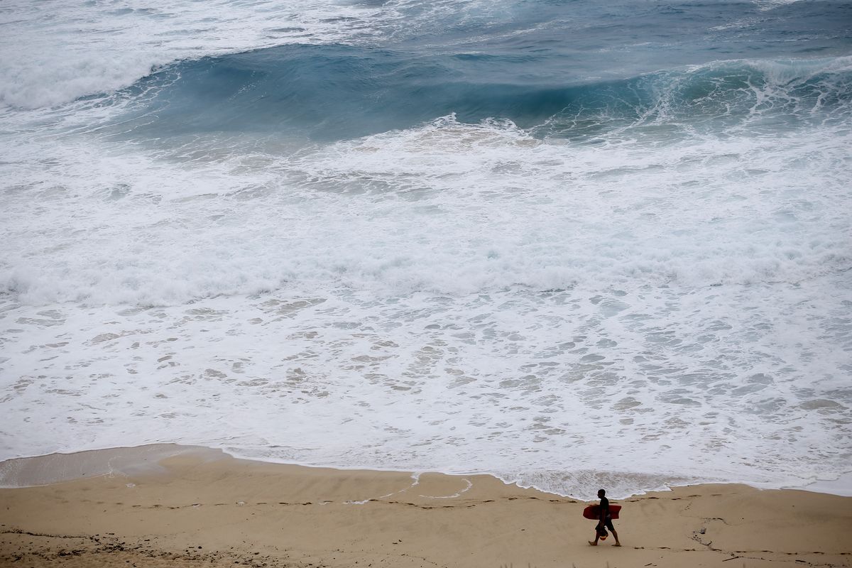 A boogie boarder walks near the surf at Makapu'u Beach, Friday, Aug. 24, 2018, in Waimanalo, Hawaii, as Hurricane Lane approaches Oahu and large ocean swells impact the coastline. In a report released Wednesday, Dec. 8, 2021, the National Academy of Sciences says to fight climate change the world needs to look into the idea of making the oceans suck up more carbon dioxide.  (Marco Garcia)