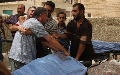 
An Iraqi man is pulled back as he cries over the body of one of two brothers who were killed in a suicide attack while lining up for jobs at an Iraqi army recruiting center in Baghdad on Sunday. 
 (Associated Press / The Spokesman-Review)