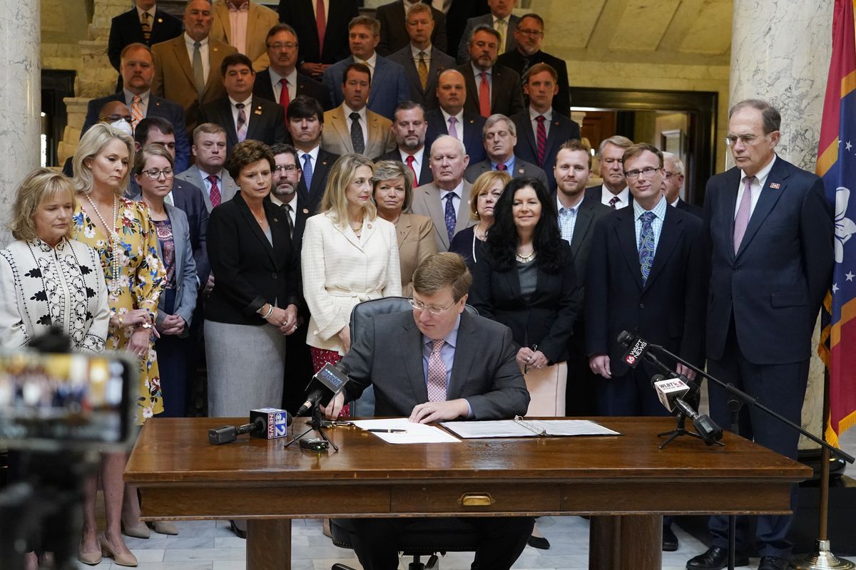Mississippi Gov. Tate Reeves signs the first state bill in the U.S. this year to ban transgender athletes from competing on female sports teams, as supporting lawmakers gather behind him, Thursday, March 11, 2021, at the Capitol in Jackson, Miss.  (Rogelio V. Solis)
