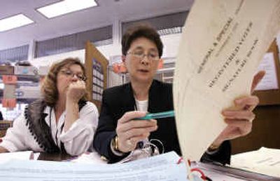 
King County election workers Linda Sanchez, left, and Colleen Kwan look over poll books Wednesday as they work to reconcile the number of voters who participated in the general election with the number of votes cast in Seattle. 
 (Associated Press / The Spokesman-Review)