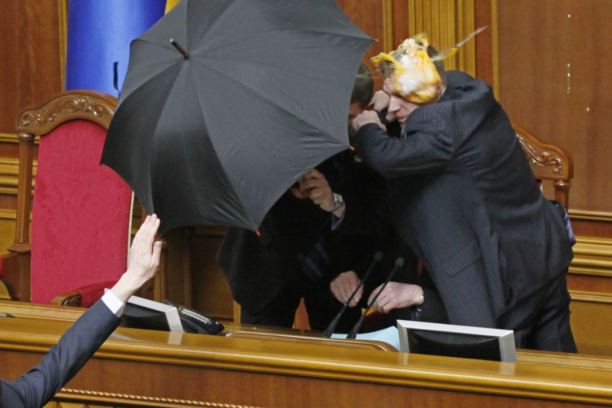 Guards cover parliament speaker Volodymyr Lytvyn with an umbrella from eggs thrown by opposition lawmakers during ratification of the Black Sea Fleet deal with Russia, in parliament in Kiev, Ukraine, on Tuesday. Associated Press photos (Associated Press photos)