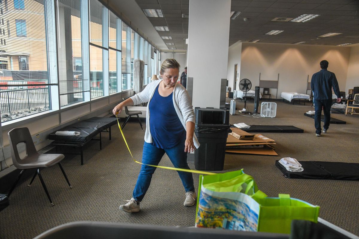 Fawn Schott, CEO of Volunteers of America, measures 6 feet of distance between sleeping mats, Monday, March 30, 2020, at the temporary shelter for the homeless in the downtown Spokane Public Library. (Dan Pelle / The Spokesman-Review)