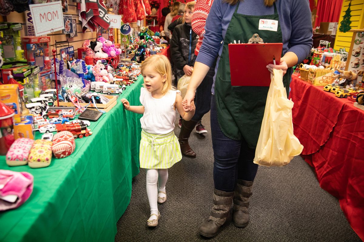 Amelia Wilson, 4, walks hand-in-hand with her "elf," Amanda Dikes, in the Santa Express shop in River Park Square on Dec. 15, 2019. The Christmas-themed temporary shop offers children the opportunity to shop for family members while accompanied by "elves" (volunteers) who guide them to gifts within their budgets. Though all gifts are between 50 cents and $10, the Vanessa Behan Crisis Nursery benefits from the proceeds. (Libby Kamrowski / The Spokesman-Review)