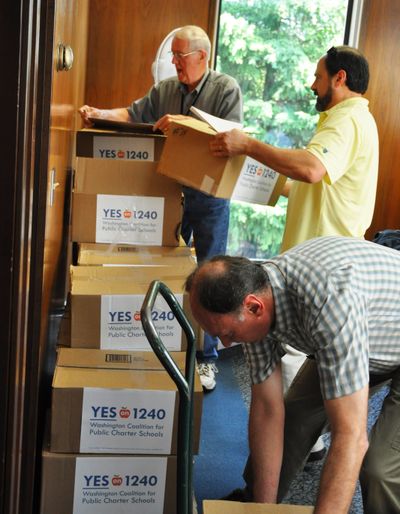 OLYMPIA -- John Michael (front) and Angelo Paparella, two supporters of an initiative to allow for charter schools, help Robert Martin of the Secretary of State's office stack boxes of petitions for I-1240 that were turned in today. (Jim Camden)